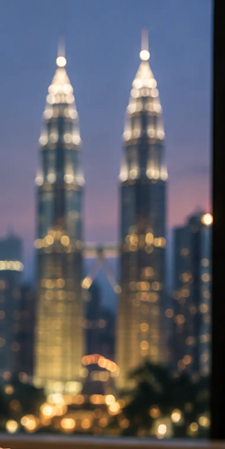 The Petronas Towers lit at dusk, seen through a condo window